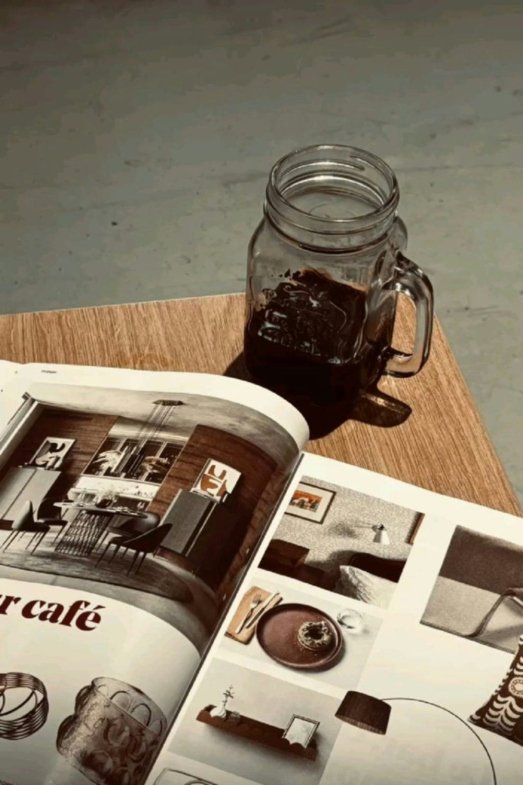 An open magazine and an iced coffee on a wooden table