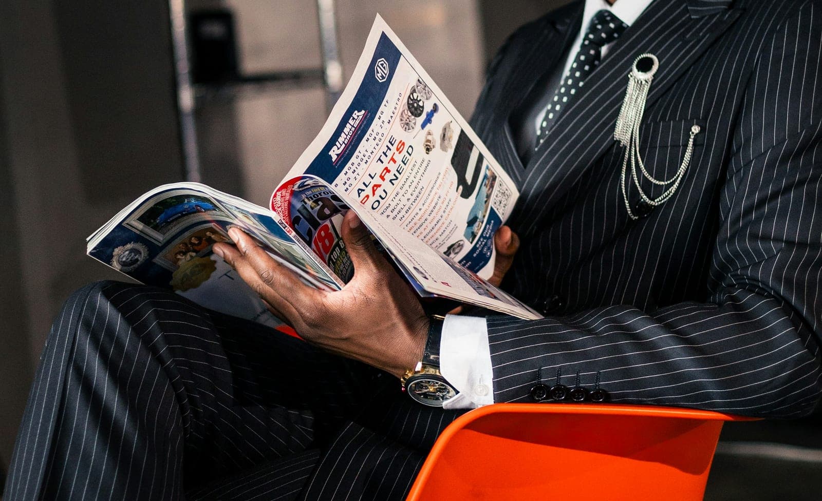A person in a pinstripe suit reading a magazine