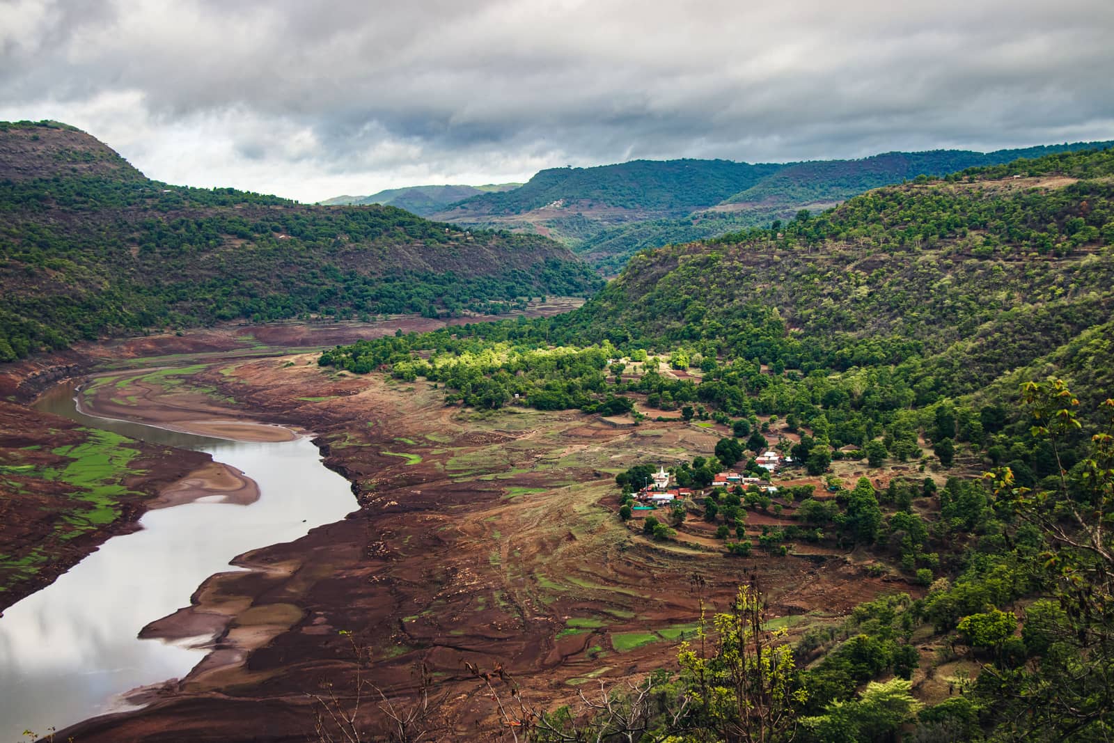 Aerial view of fields and a dry river bed among low hills