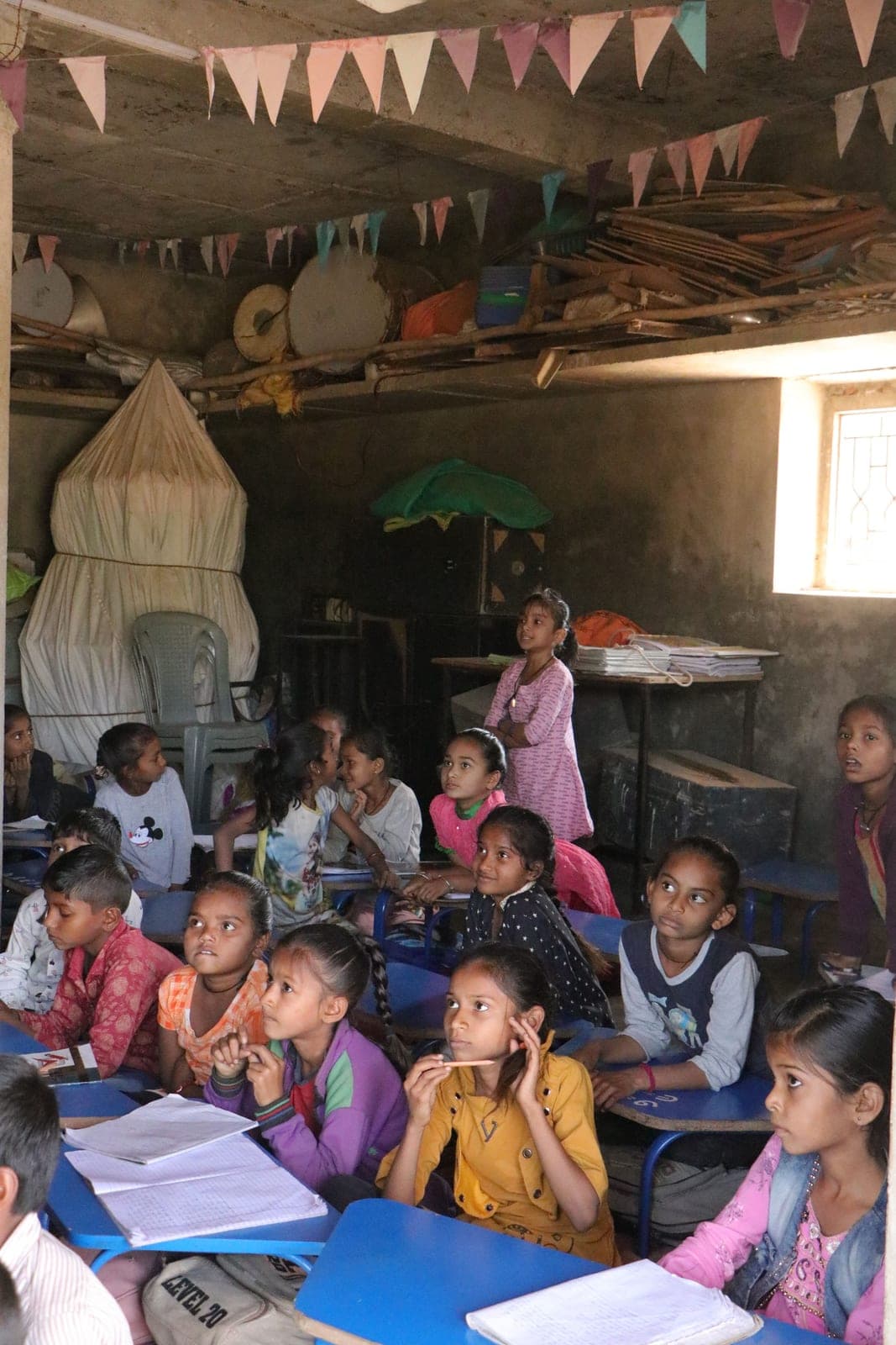 Young girls at desks in a village primary school, writing in notebooks