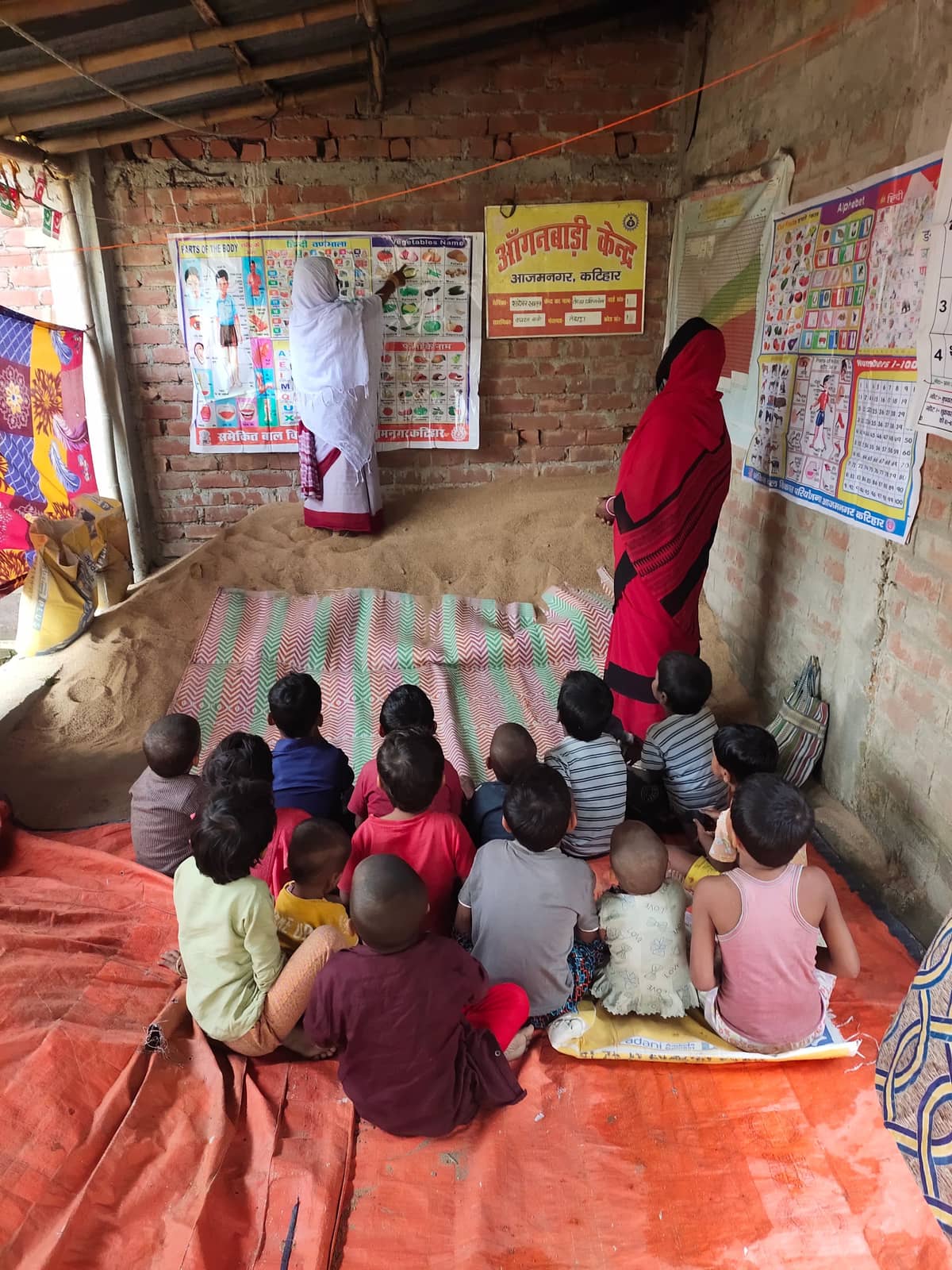 Children sitting on the floor of a rural classroom with slates and notebooks