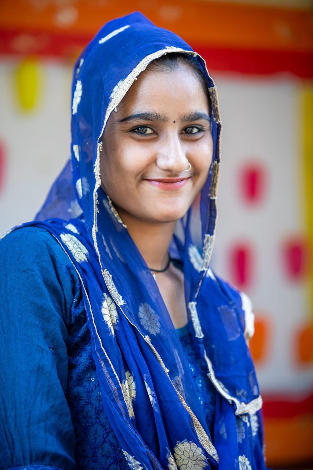 A young woman in a blue head covering, smiling