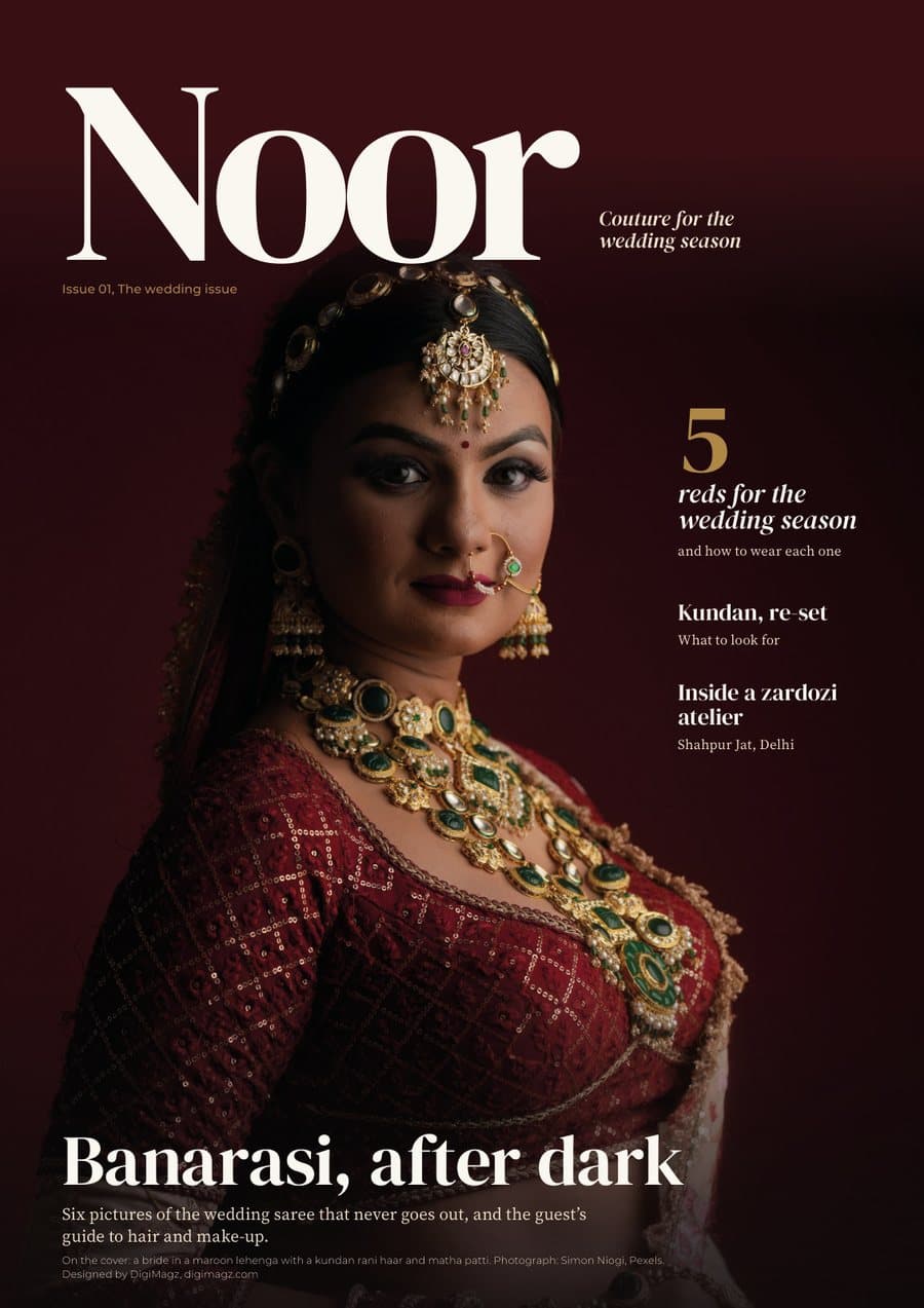 Noor cover: a bride in a maroon lehenga with a kundan rani haar against a deep red wall, masthead Noor, lead line Banarasi, after dark