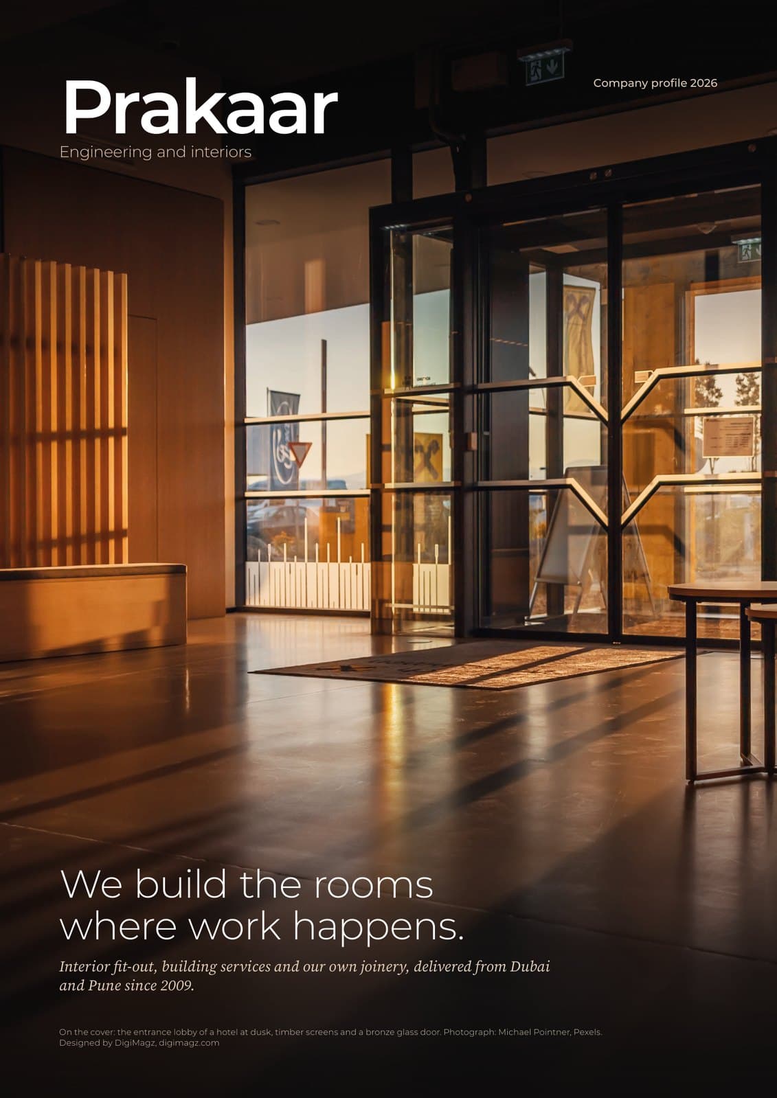 Cover of Prakaar company profile 2026: a lit glass-fronted office interior at dusk, with the line We build the rooms where work happens, designed by DigiMagz