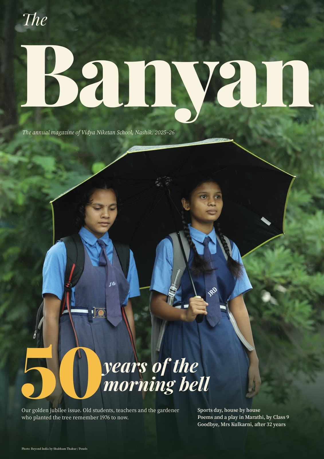 Cover of The Banyan, the 2025–26 annual magazine of a Nashik school: two schoolgirls in blue uniforms under a black umbrella; lead line 50 years of the morning bell, designed by DigiMagz